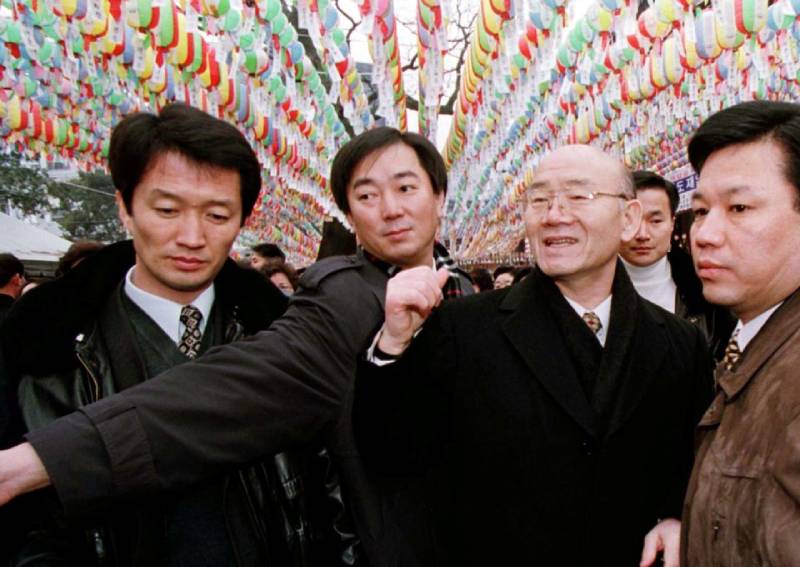 Former South Korean president Chun Doo-hwan, surrounded by bodyguards, walks under Buddhist prayer lanterns at the Chogye temple in Seoul on Dec 30, 1997.