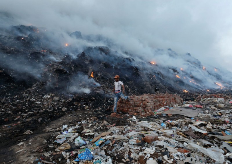 Shiekh Shahidul, 18, walks past the burning garbage at the Bhalswa landfill site in New Delhi, India, on April 27, 2022.