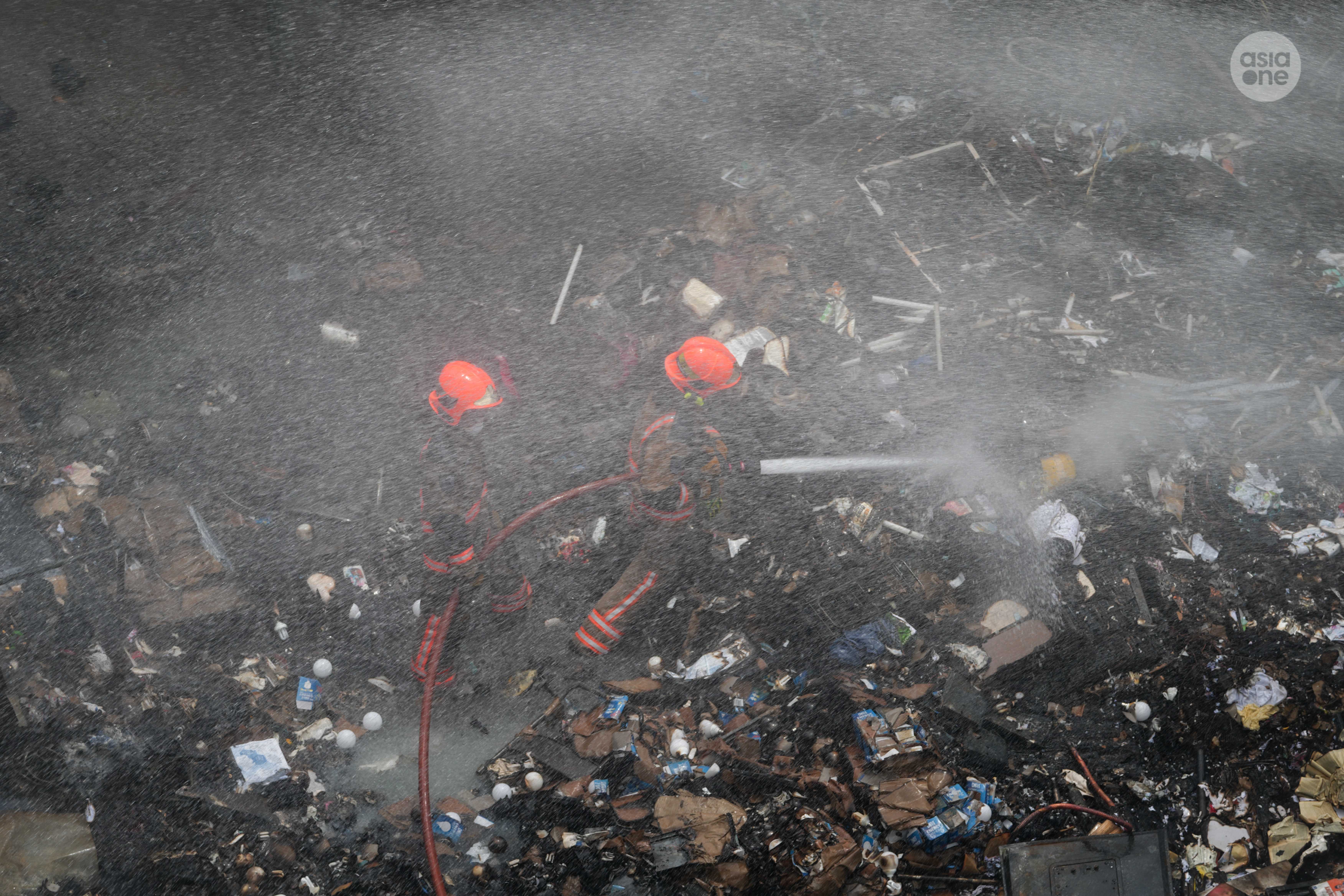 SCDF firefighters conducting dampening down operation.