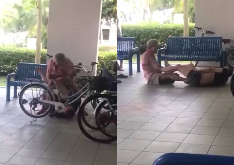Two elderly men brawling at a void deck while most others stand or sit idly by, watching.