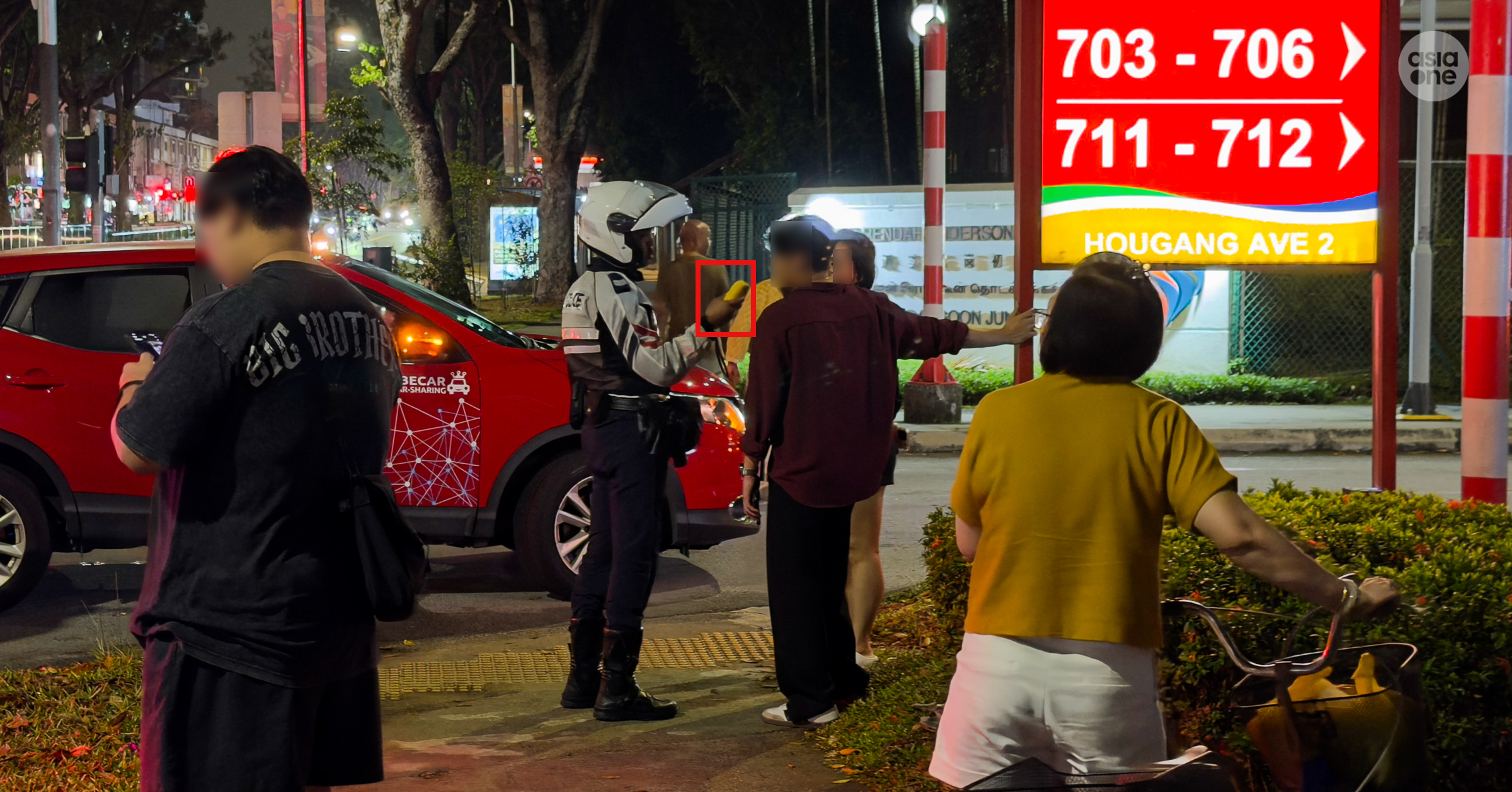 A Traffic Police officer administering a breathalyser test on the male driver.