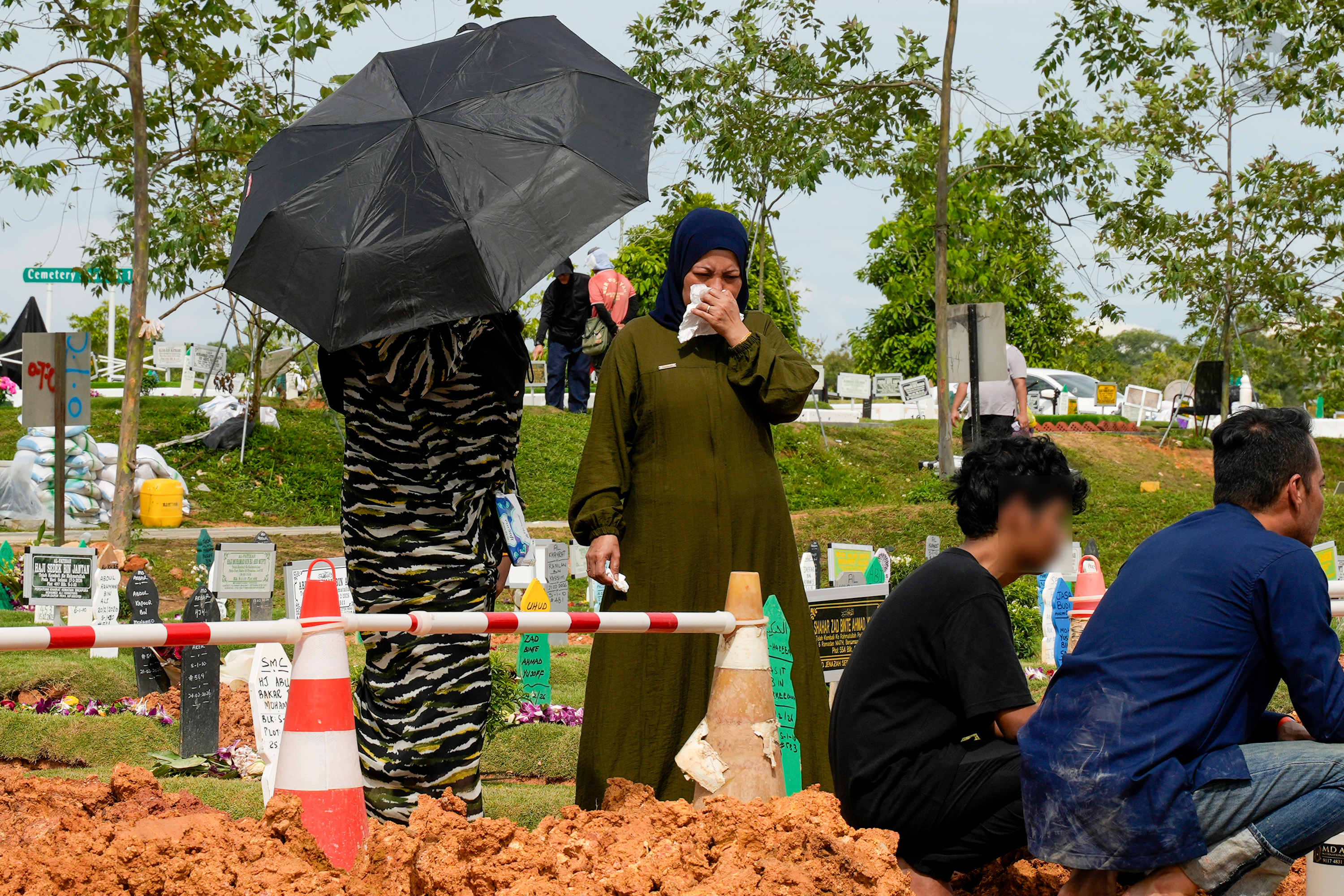 Madam Siti wiping away tears as she looked at Daniel's grave.