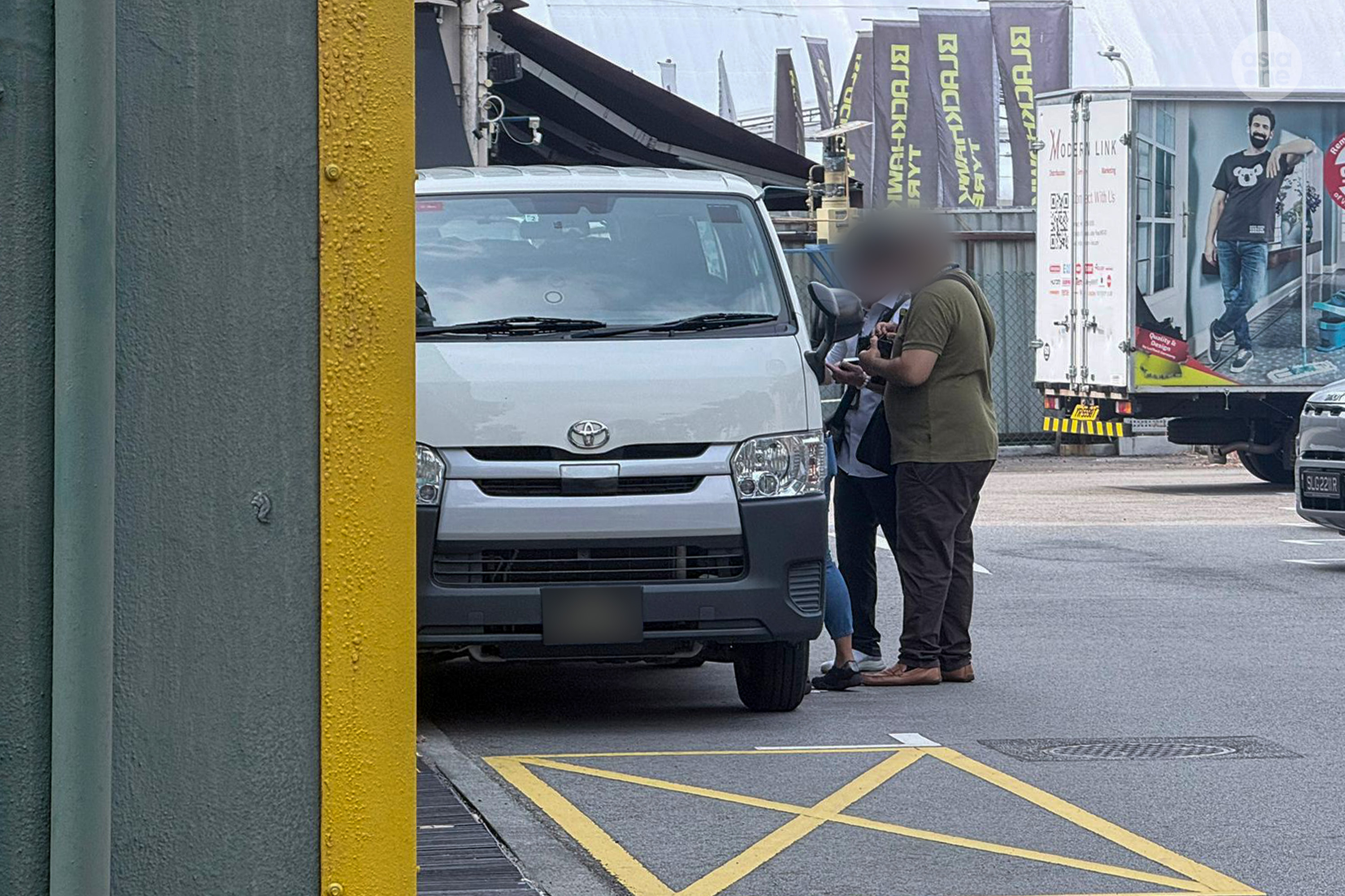 Two men, believed to be directors of a construction company in Paya Lebar, led to a waiting van by MOM enforcement officers.