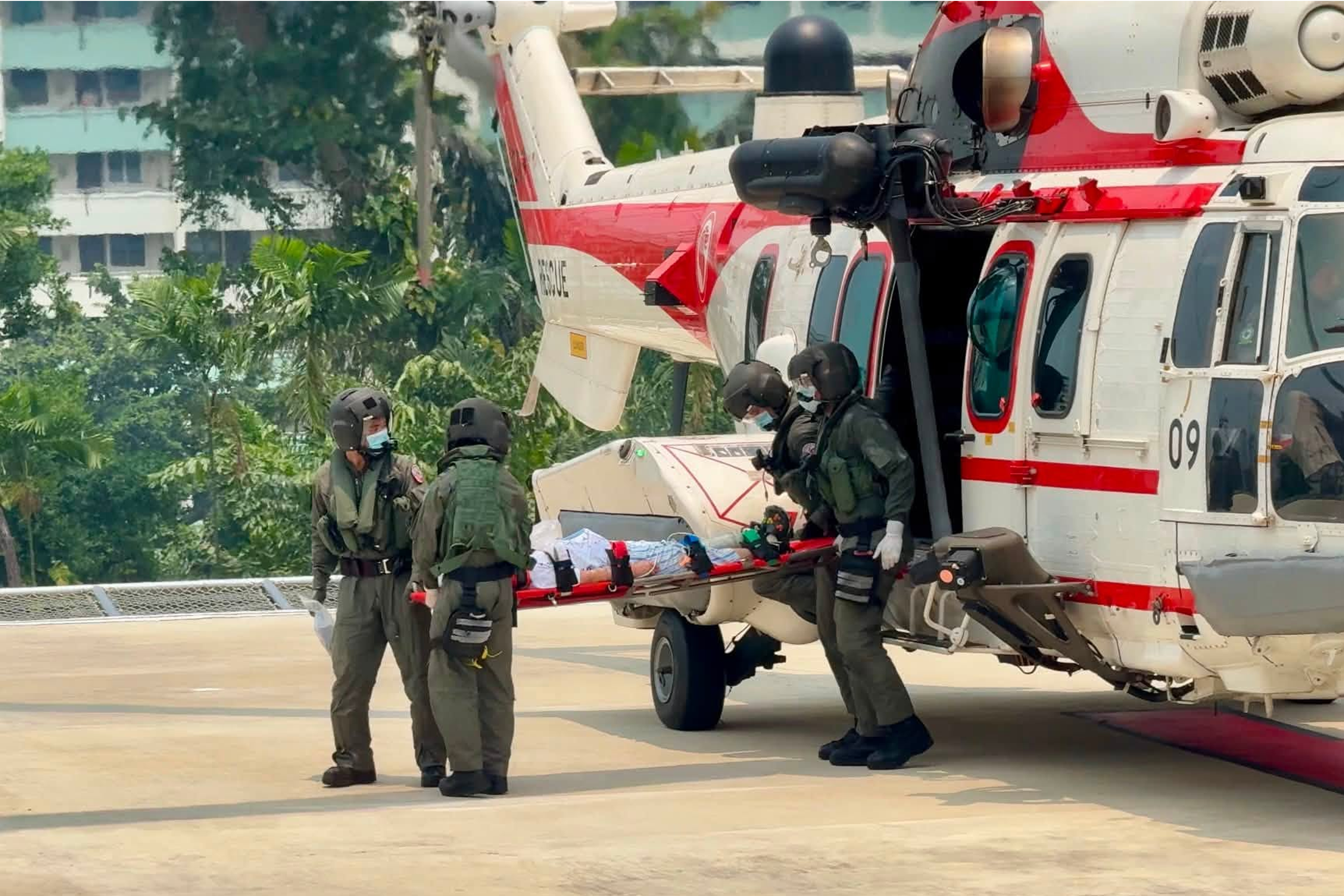 RSAF personnel from 1 Medical Squadron and the helicopter's crew carrying the patient out of Rescue.