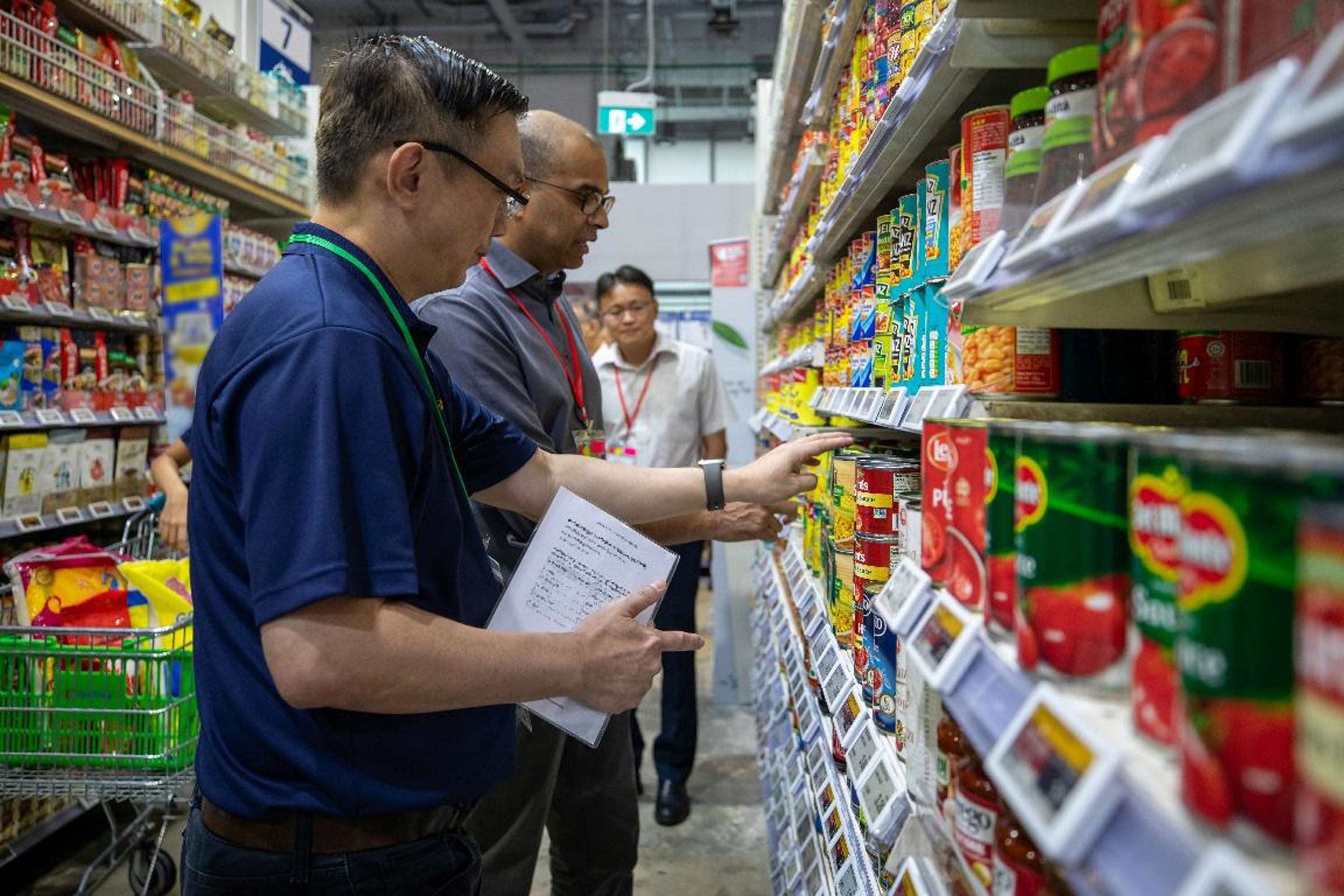 Senior Minister of State Dr Janil Puthucheary observing retail operations at an outlet following the earlier distribution of stockpiled food supplies from a warehouse.
