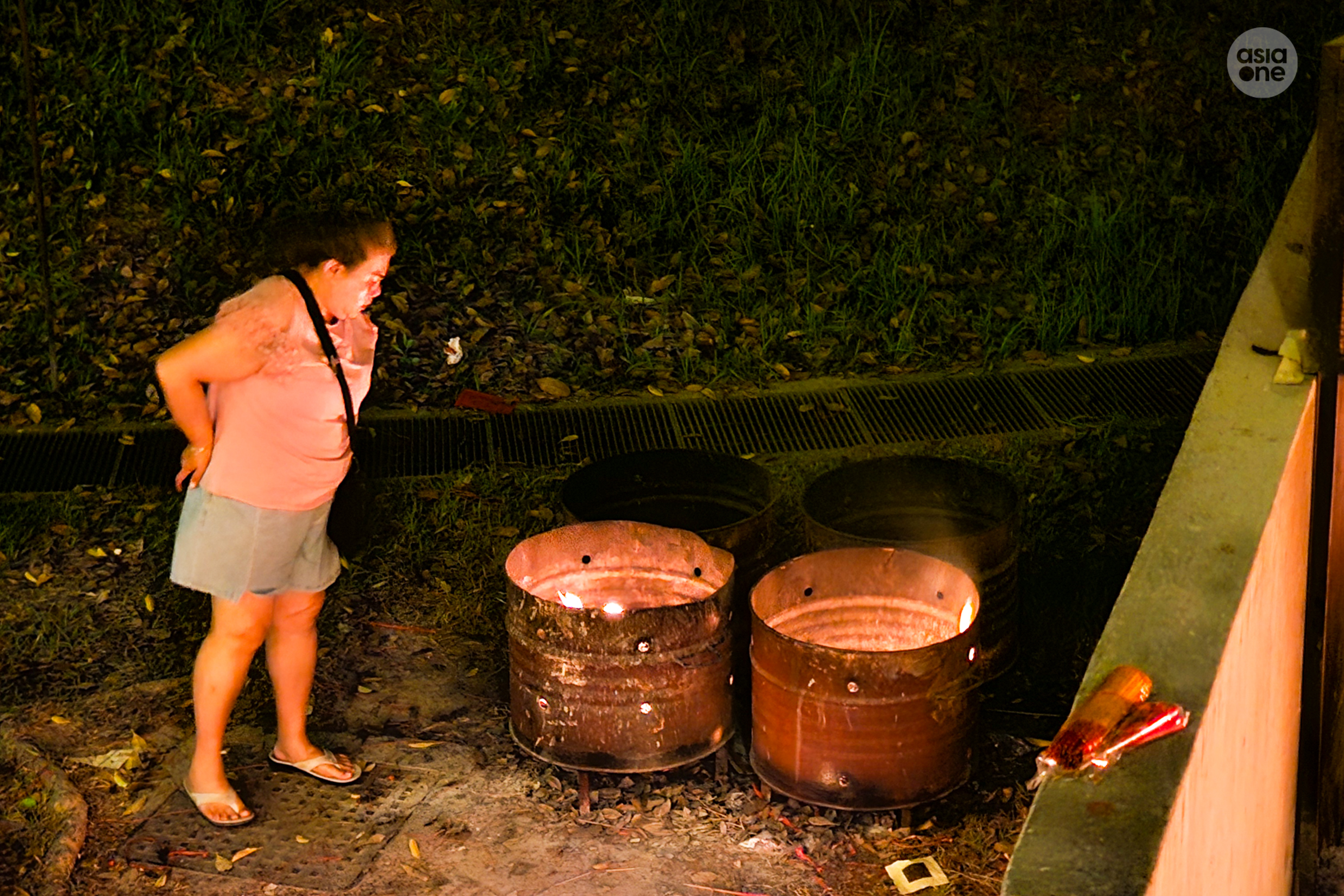 A woman checks to ensure that her offerings are properly burnt before leaving Mandai Columbarium during Qing Ming.