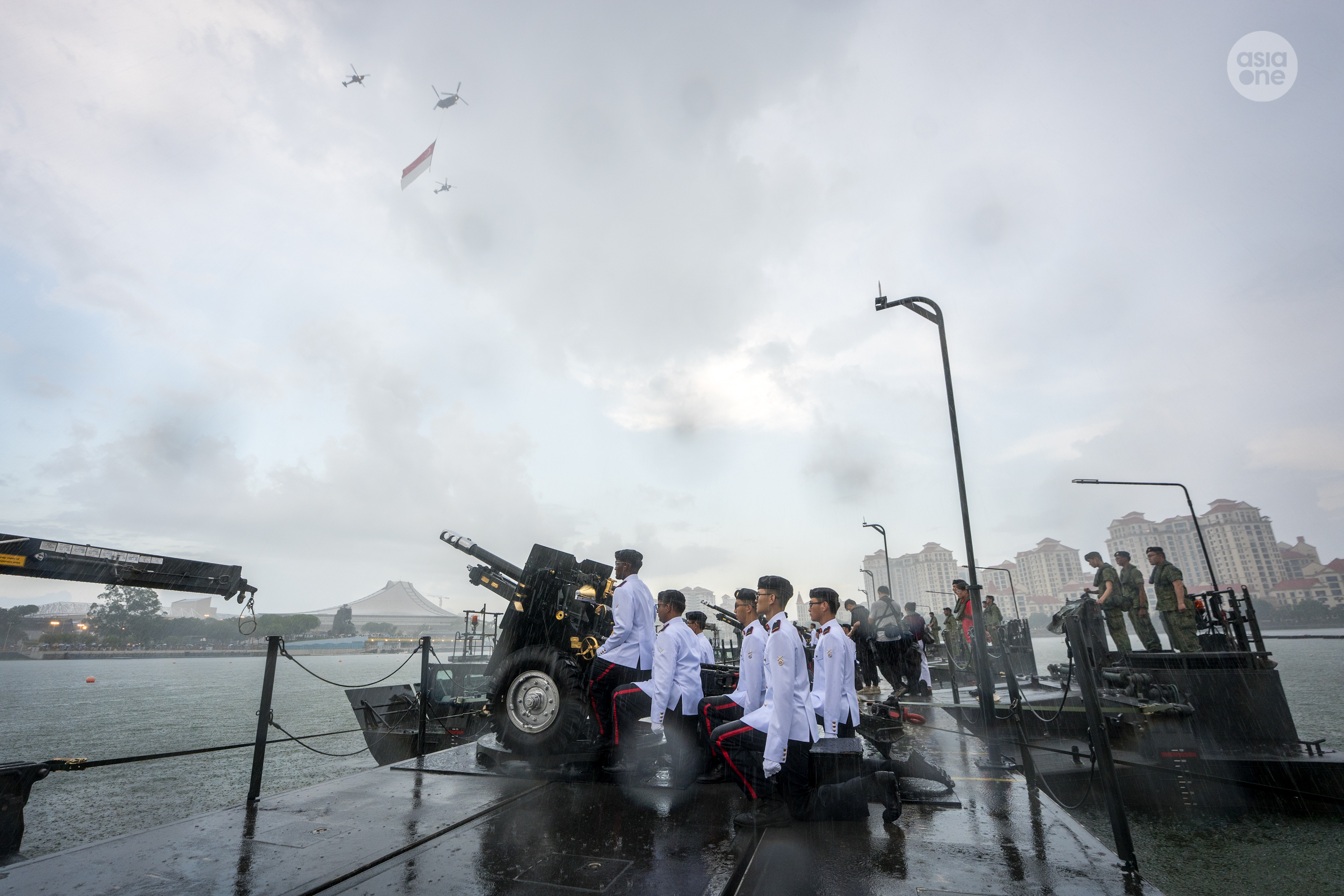 A CH-47 Chinook, escorted by two AH-64 Apache attack helicopters, passes the Presidential Gun Salute crew as it approaches the National Stadium for the state flag flypast.
