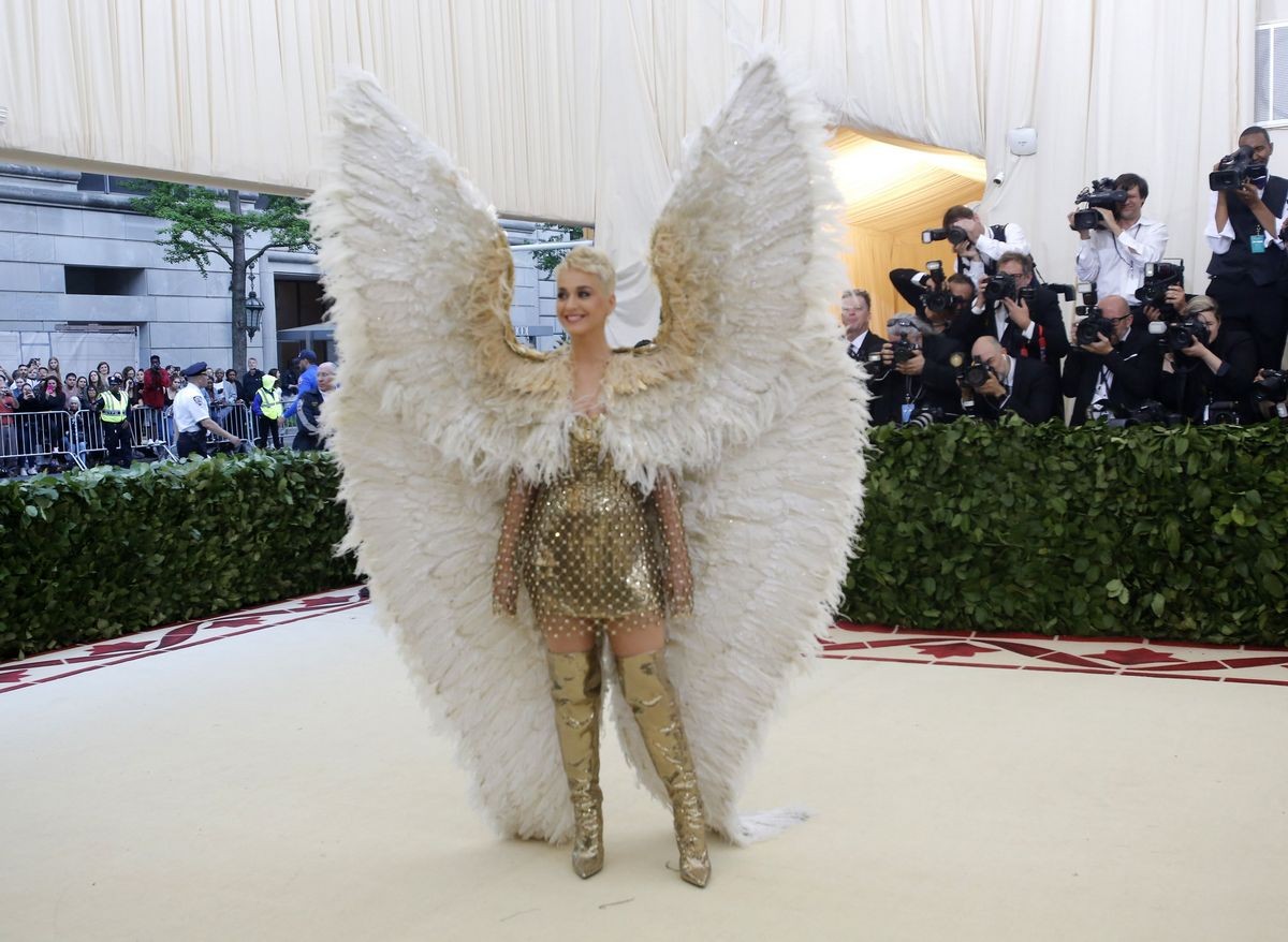 Singer Katy Perry wowed in enormous, feathered white wings resembling an archangel over a Versace gold mini-dress paired with thigh-high gold boots.