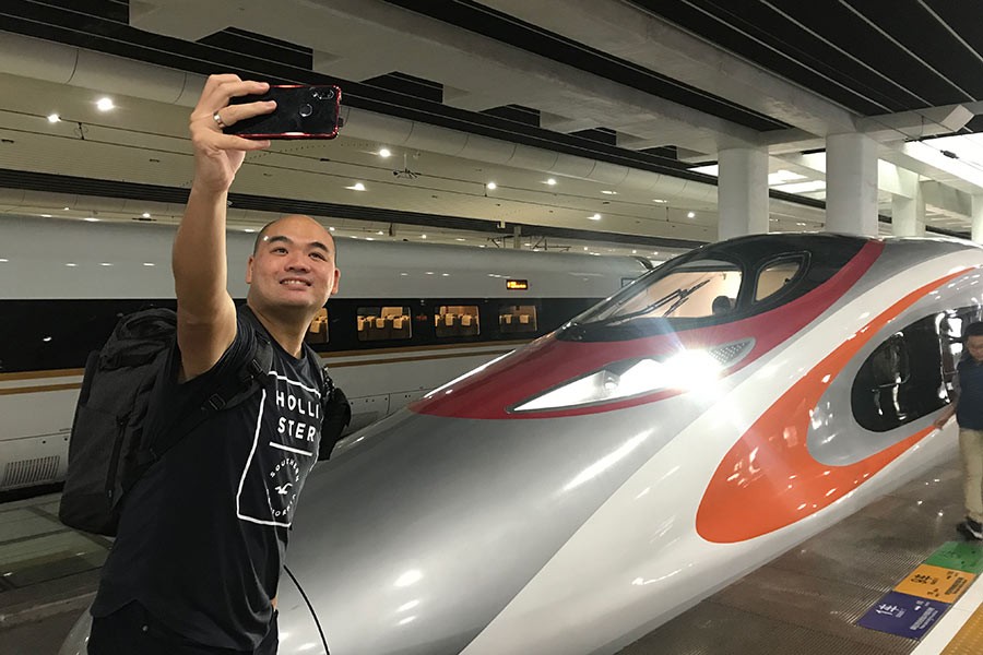 A passenger takes a selfie in front of a Vibrant Express train at Guangzhou South Station, South China's Guangdong province, after exiting the Vibrant Express train following its first run from Hong Kong to Guangzhou, Sept 23, 2018.
